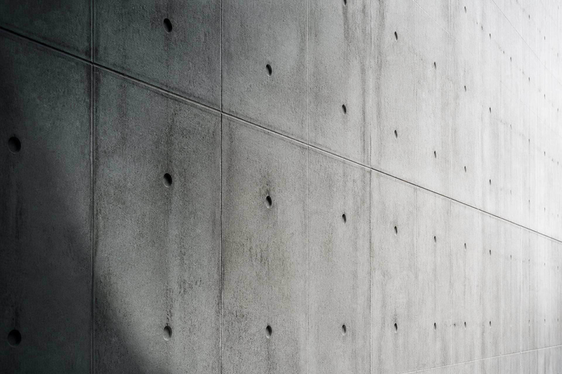 Board-formed cast-in-place concrete wall with tie-rod holes in raking light